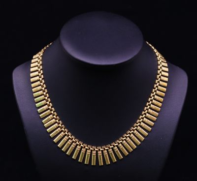 a gold necklace on a mannequin with a black background