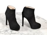 une paire de bottines en daim noir posées sur une table en marbre