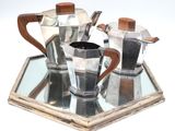 a silver tea set on a mirrored tray with a wooden handle