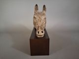 sculpture of a horse ' s head on a wooden block on a white background