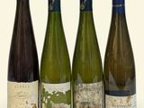 four bottles of wine are lined up on a white surface
