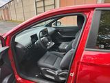 the interior of a red car with the driver ' s door open
