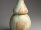 un vase vert et blanc posé sur une surface grise