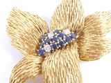 gold tone flower brooch with blue and white stones in center