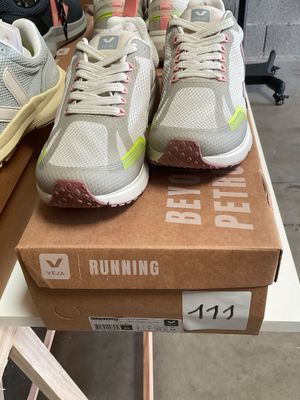 two pairs of running shoes sitting on top of a box on a table