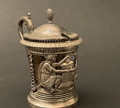 a silver vase sitting on a table with a bird on it