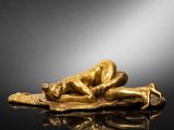 a gold figurine of a sleeping man on a pillow