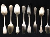 de nombreuses cuillères et fourchettes en argent sur une table noire