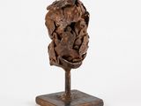 sculpture of a head on a wooden base on a white background