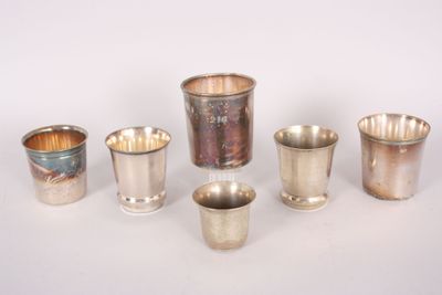 several silver cups and cups are lined up on a white surface