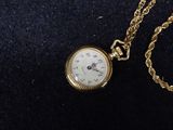 a gold pocket watch with a chain on a black surface
