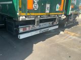 a green garbage truck that is parked in the parking lot