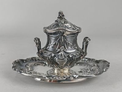 an antique silver plate with a teapot on it on a white surface