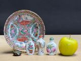 a plate, a bowl, and two miniature figurines next to an apple