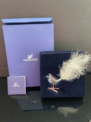 une petite plume blanche dans une boîte bleue, à côté d'une boîte violette