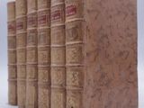 several old books are stacked on top of each other on a white surface