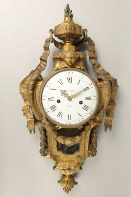 a gold clock hanging on the wall next to a wall clock