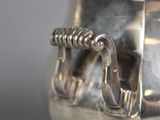 an antique silver tea pot with a handle on a table