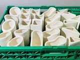 une caisse en plastique verte remplie de tasses et de bols blancs