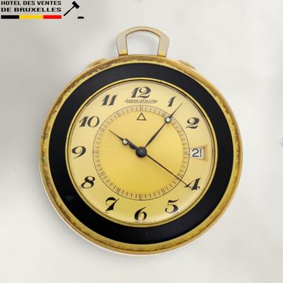 une horloge dorée et noire accrochée à un mur blanc