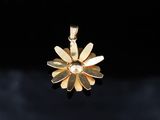 a close up of a gold flower pendant on a black background