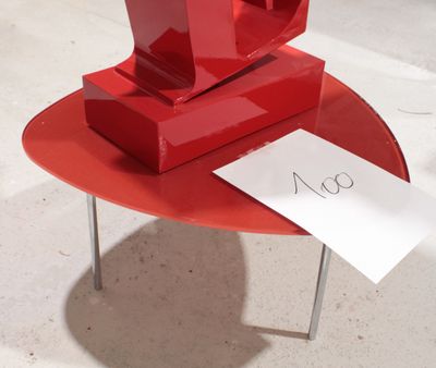 une sculpture rouge posée sur une table rouge, sur laquelle se trouve un mot