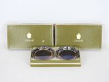 deux paires de lunettes se trouvent dans une boîte posée sur une surface blanche