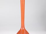 un vase orange posé sur une table blanche