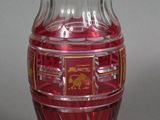 a glass vase with a red and gold design on it