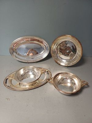 trois plats en métal argenté posés sur une table, avec un miroir au milieu