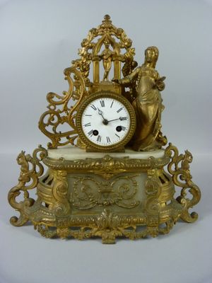 une horloge en or posée sur une table blanche