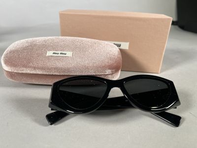 sunglasses with black frames and a pink case sitting on a table