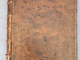 un vieux livre marron posé sur une table blanche