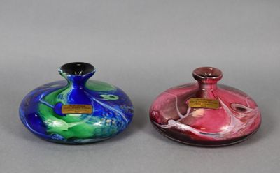 three different colored glass vases sitting next to each other on a gray surface