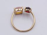 a close up of a gold ring with two different colored stones on it