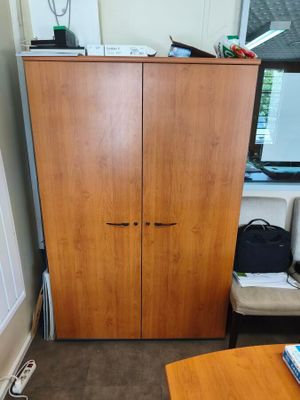 a wooden cabinet in the corner of a room next to a window