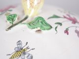 a close up of a plate with a flower and a bee on it