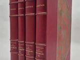 quatre livres rouges sont empilés les uns sur les autres sur une surface blanche