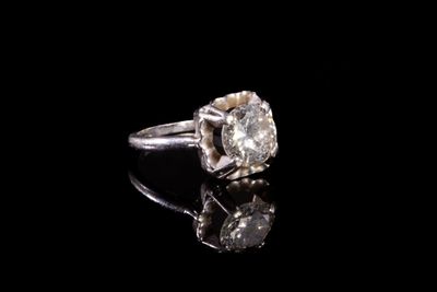 une image d'une bague en diamant sur une surface noire