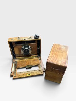 an old wooden box with a camera in it sitting next to a wooden box