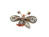 a close up of a brooch with orange beads on a white background