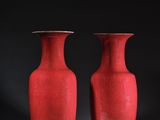une paire de vases rouges posés sur une table, sur fond noir