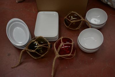 de nombreux bols et assiettes posés par terre à côté d'un carton