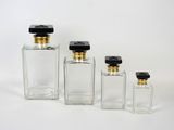 trois bouteilles en verre transparent avec des couvercles noirs et des bouchons dorés