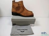 des bottines marron à talons, présentées dans une boîte à côté d'un sac gris