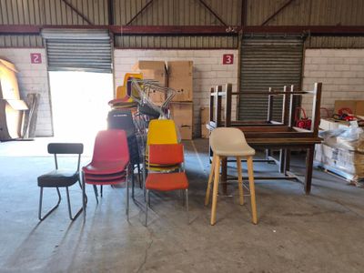 de nombreuses chaises et tables dans un entrepôt, avec un homme debout près d'une table