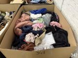 a cardboard box full of clothes sitting on the ground