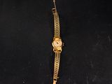 a gold watch on a black cloth with a chain around it
