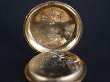 a close up of a gold pocket watch on a black surface