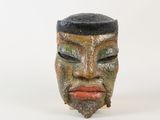 un masque en céramique coiffé d'un chapeau noir